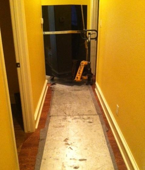 a gun safe being rolled through a house over plates on a pallet jack 3