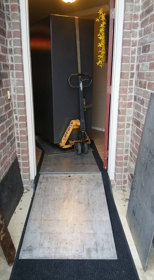 Cabela's gun safe strapped on pallet jack being moved out through front door of house on runners and aluminum plates over threshold
